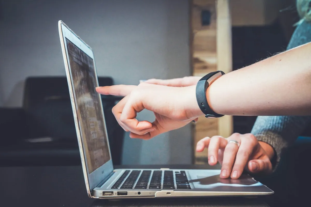 Hands pointing at a laptop during a technology review