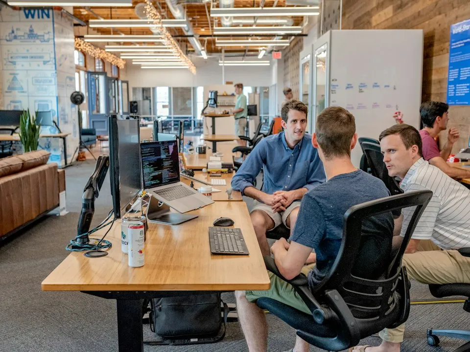 Technology team discussing work around a table in an open office