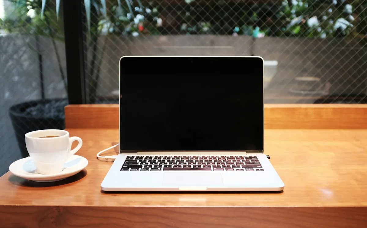 Laptop with a blank dark screen and coffee on a desk